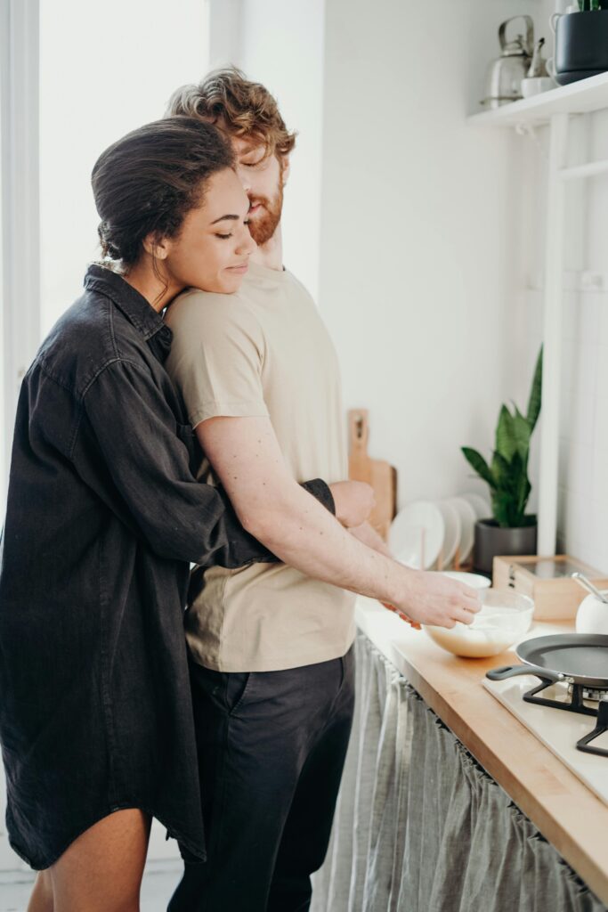 Young couple embracing in a cozy kitchen, sharing a moment of love and affection.